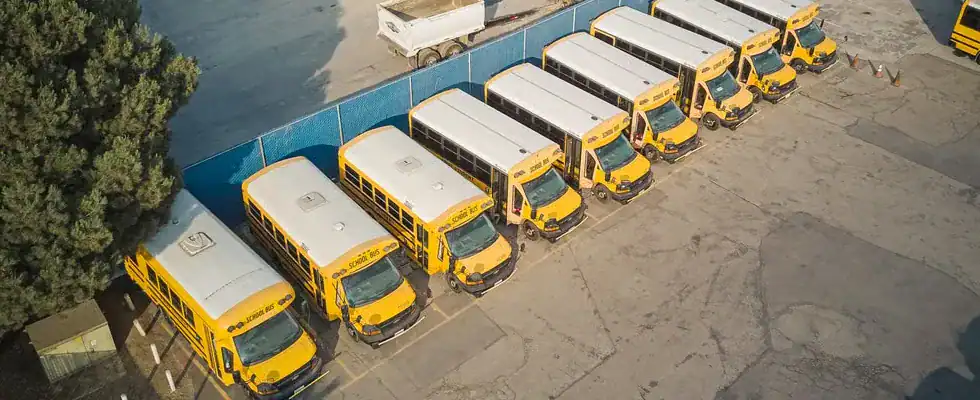Aerial view of school buses and trucks parked in an industrial lot