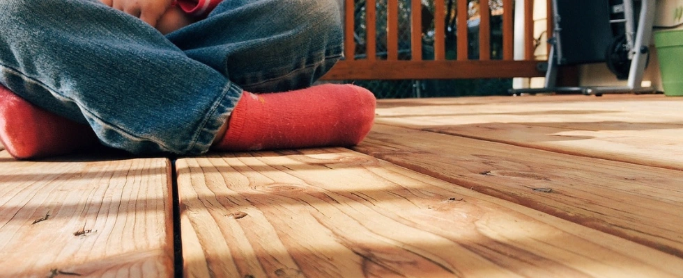 kid sitting cross-legged on a wood deck
