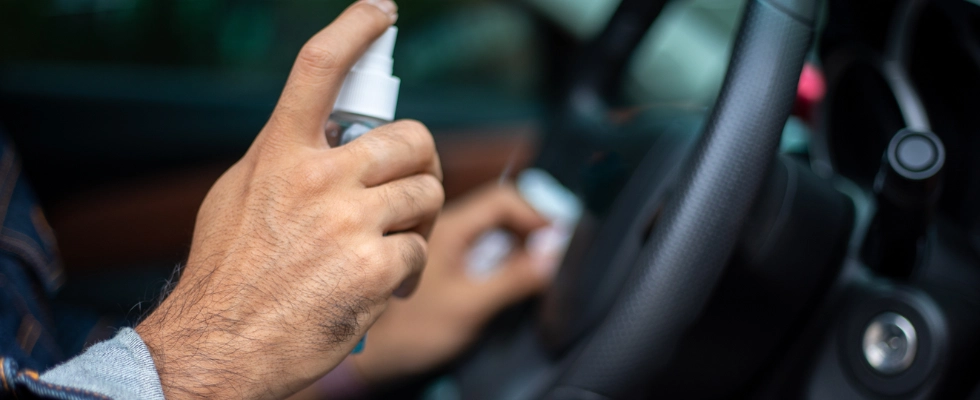 Man using rubbing alcohol spray and water solution to clean windshield