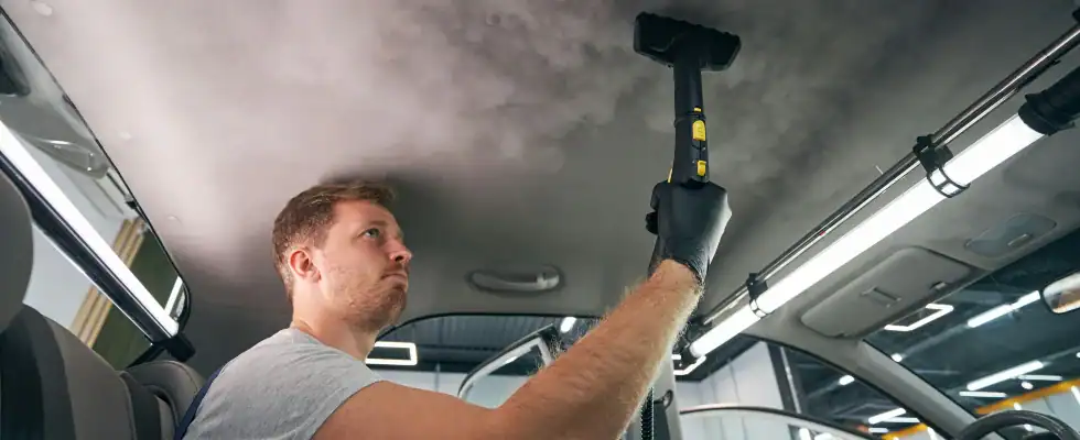 Service worker using vapor cleaner for automobile cabin. Steam sterilizing. Dry cleaning car salon