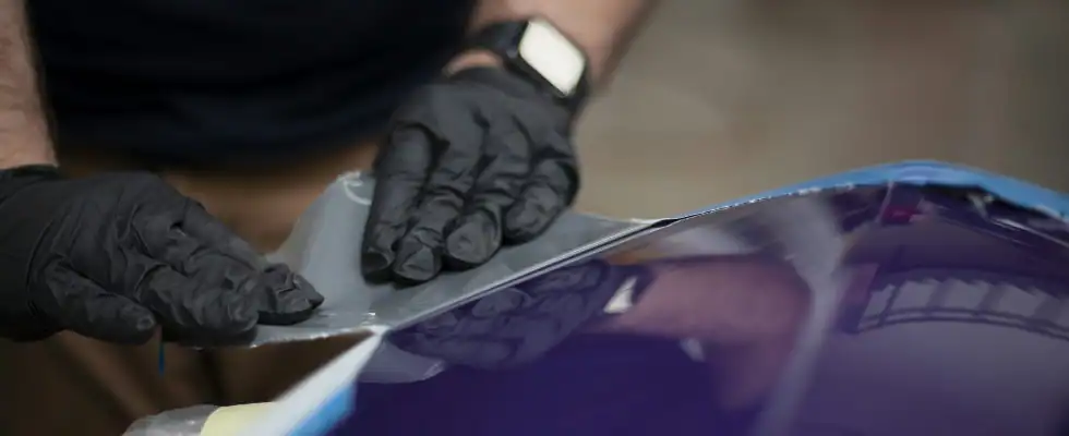 a man in black gloves waxing a blue car