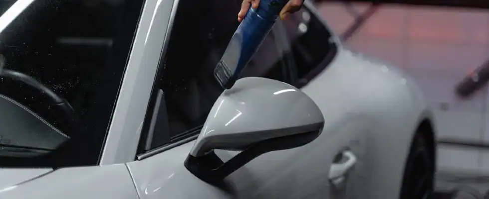 detailer cleaning white sports car with vacuum hose