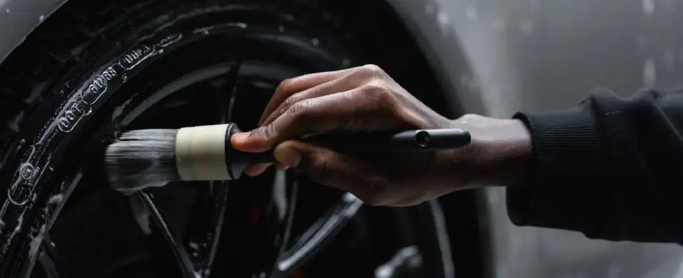 detailer using a brush to clean car wheels